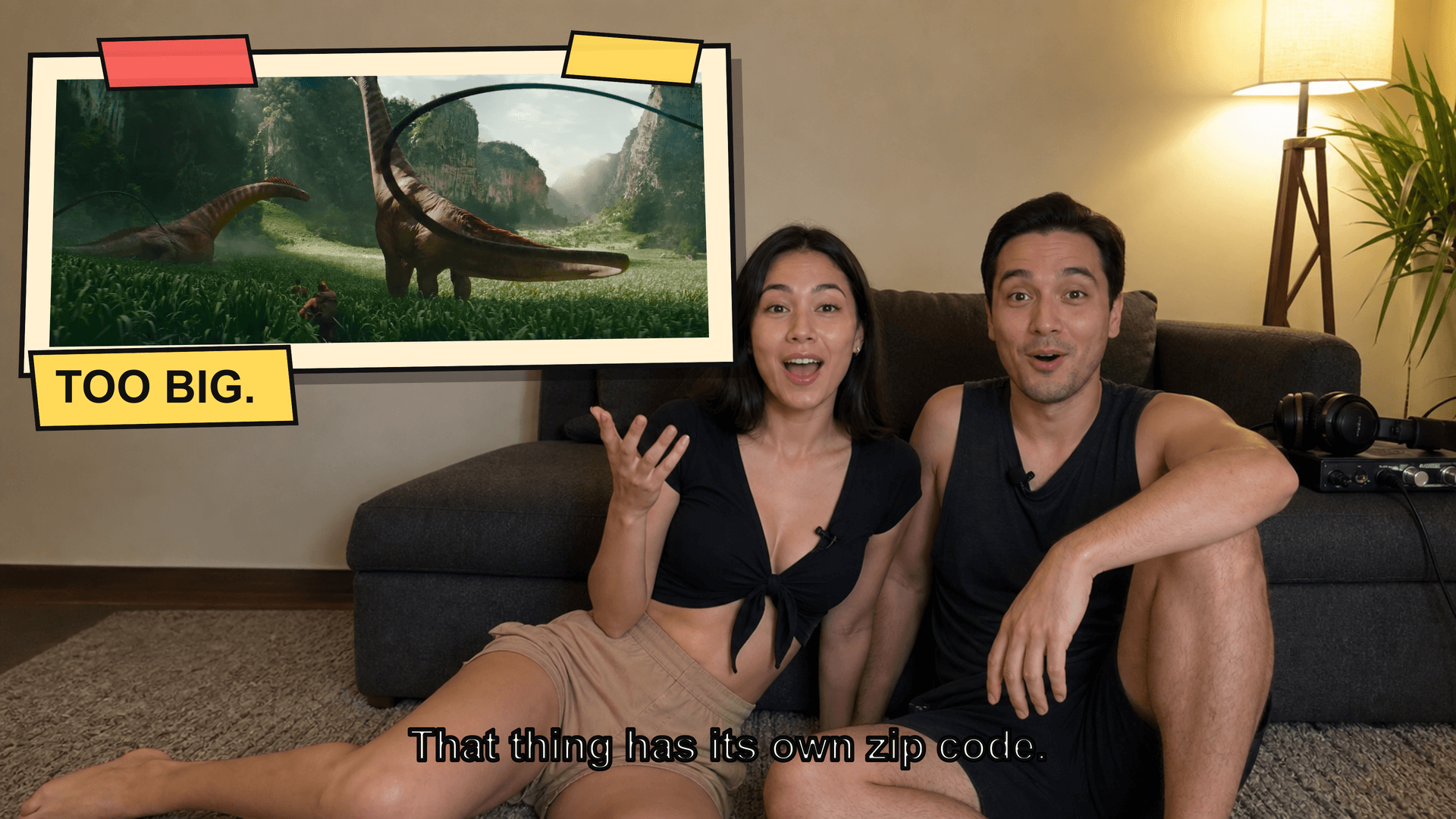 大型画面の映画に驚くソファの二人と、その様子を収録する三脚カメラ